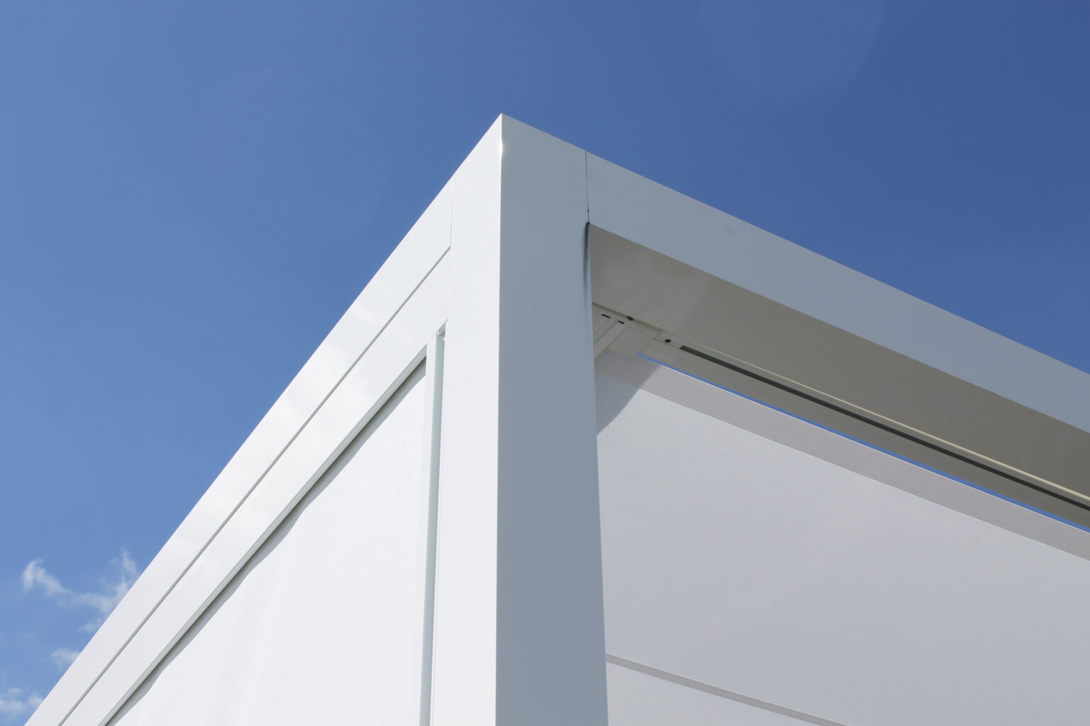 Eckdetail einer weißen Varisol Q.bus Pergola mit textilem Sonnenschutz vor blauem Himmel