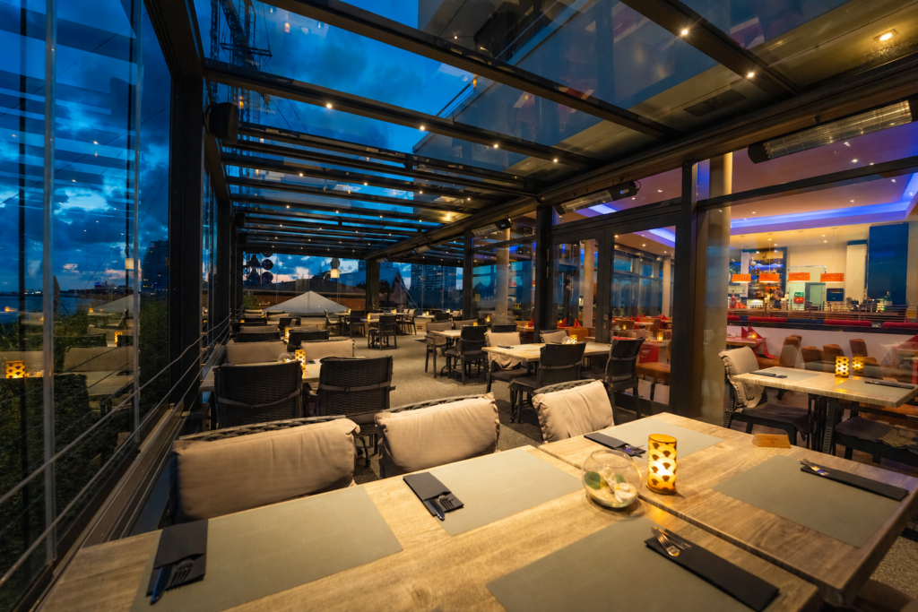Glasdach über einer Restaurantterrasse mit seitlicher Verglasung und Beleuchtung